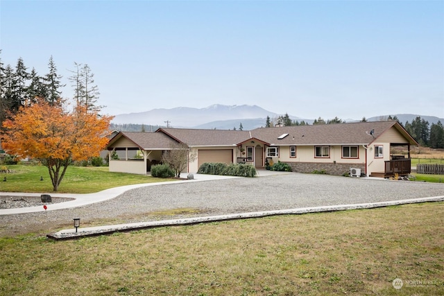 ranch-style home featuring a mountain view, a garage, and a front yard