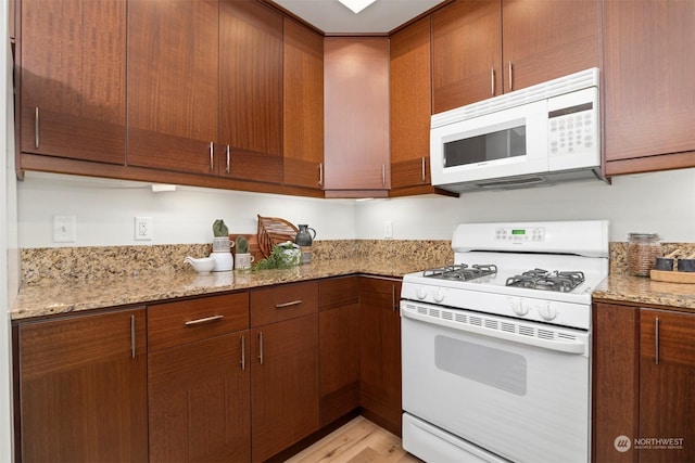 kitchen featuring light stone counters, white appliances, and light hardwood / wood-style floors