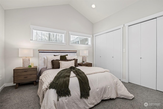 carpeted bedroom featuring multiple closets and vaulted ceiling