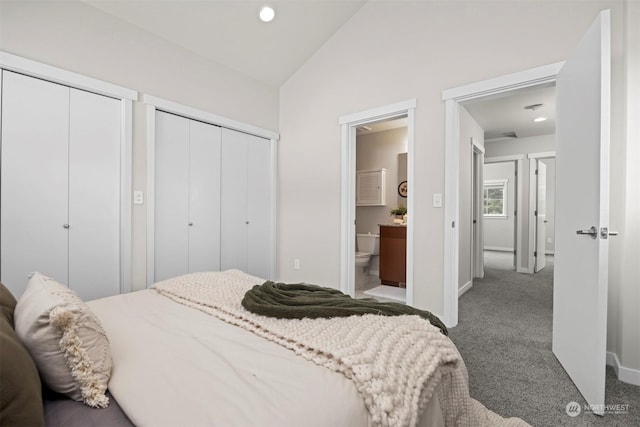 carpeted bedroom with multiple closets, ensuite bath, and vaulted ceiling