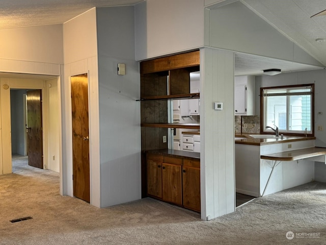 kitchen with light colored carpet, sink, and vaulted ceiling