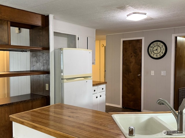 kitchen with white cabinets, sink, dark hardwood / wood-style floors, a textured ceiling, and white fridge