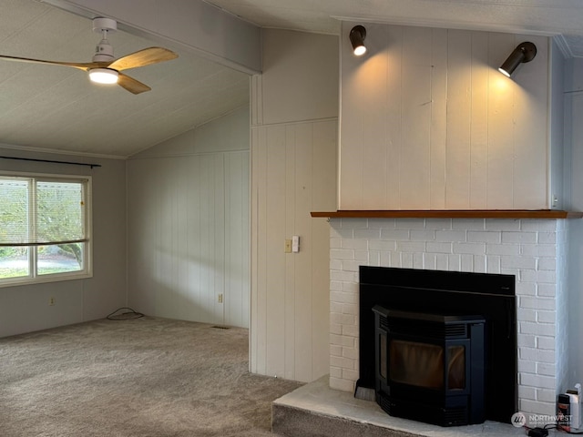 unfurnished living room with carpet flooring, a wood stove, ceiling fan, vaulted ceiling, and wooden walls