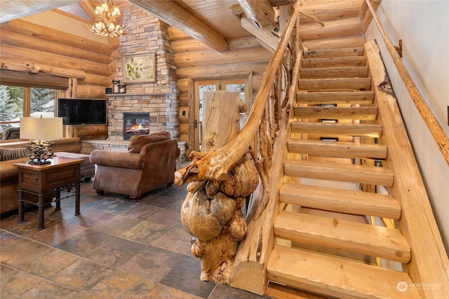 stairs with beamed ceiling, an inviting chandelier, rustic walls, and a fireplace