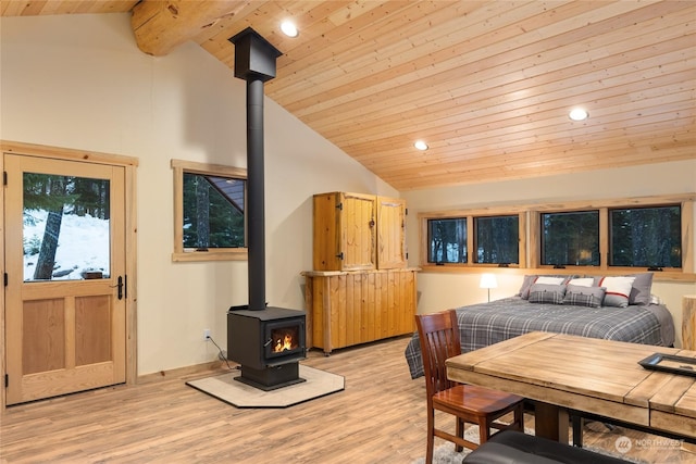 interior space with wood ceiling, light hardwood / wood-style flooring, high vaulted ceiling, and a wood stove