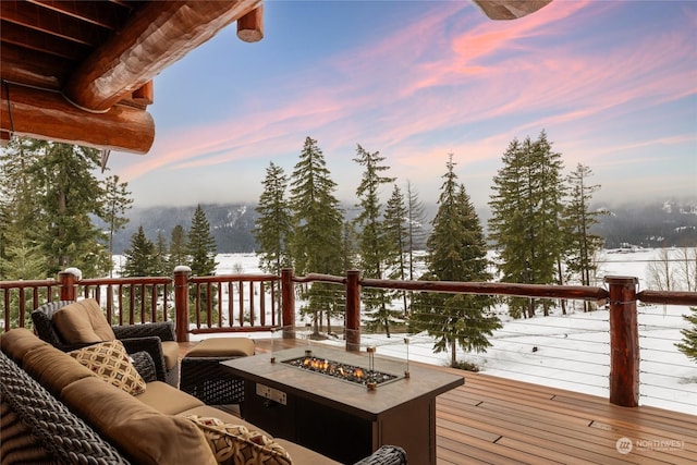 snow covered deck with an outdoor living space with a fire pit