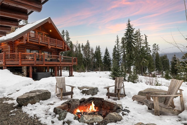 yard covered in snow featuring a deck and an outdoor fire pit