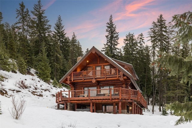 snow covered rear of property with a wooden deck