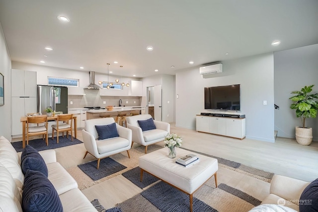 living room with an AC wall unit, sink, and light hardwood / wood-style flooring