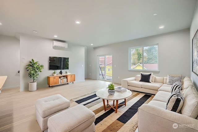 living room with light hardwood / wood-style floors and a wall unit AC