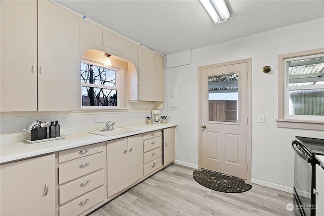 kitchen with light wood-type flooring, black range with electric cooktop, and sink