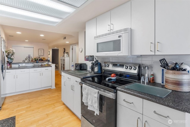 kitchen featuring white cabinetry, appliances with stainless steel finishes, light hardwood / wood-style floors, and decorative backsplash