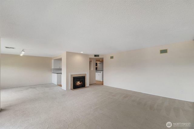 908 E Bay Dr NE Unit 203, Olympia, WA 98506 - unfurnished living room featuring light colored carpet, a fireplace with flush hearth, and a textured ceiling