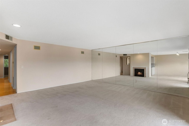 908 E Bay Dr NE Unit 203, Olympia, WA 98506 - unfurnished living room with light colored carpet, a lit fireplace, and recessed lighting