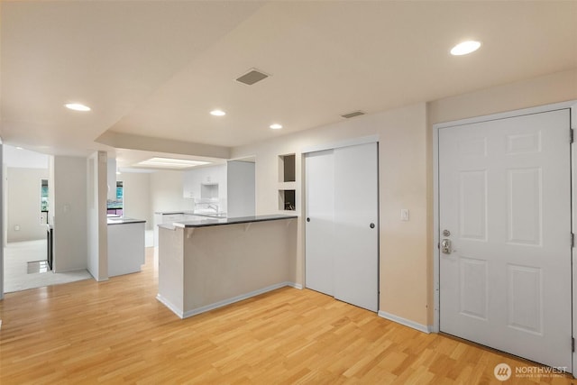 908 E Bay Dr NE Unit 203, Olympia, WA 98506 - kitchen featuring a peninsula, light wood finished floors, recessed lighting, white cabinetry, and baseboards