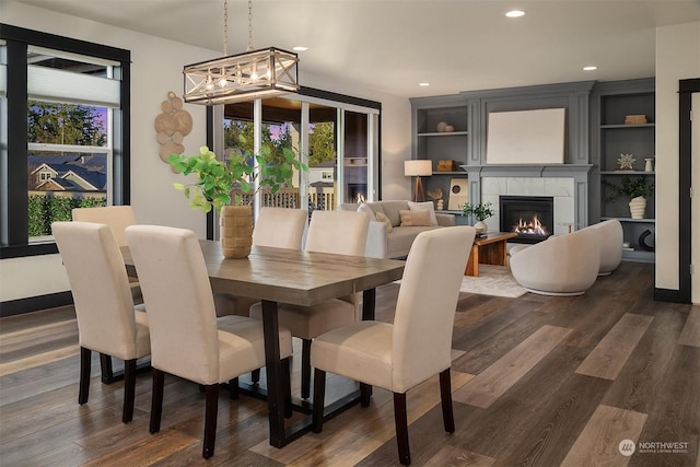 dining room with a fireplace, built in features, and dark hardwood / wood-style floors