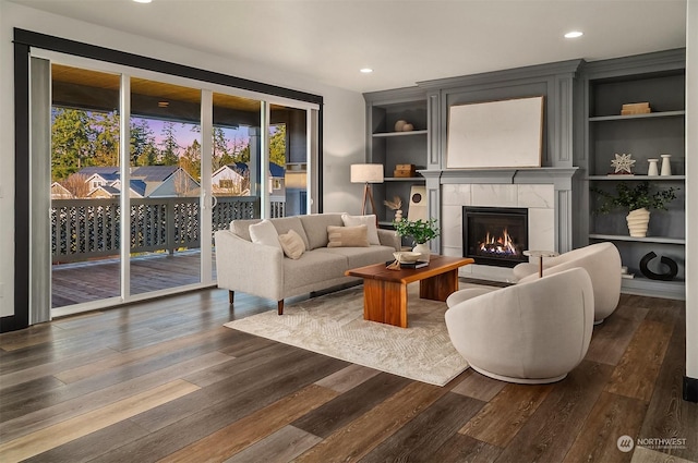 living room with a fireplace, dark hardwood / wood-style flooring, and built in shelves