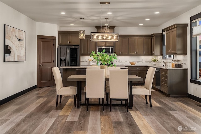 kitchen with sink, dark wood-type flooring, hanging light fixtures, a kitchen island, and appliances with stainless steel finishes