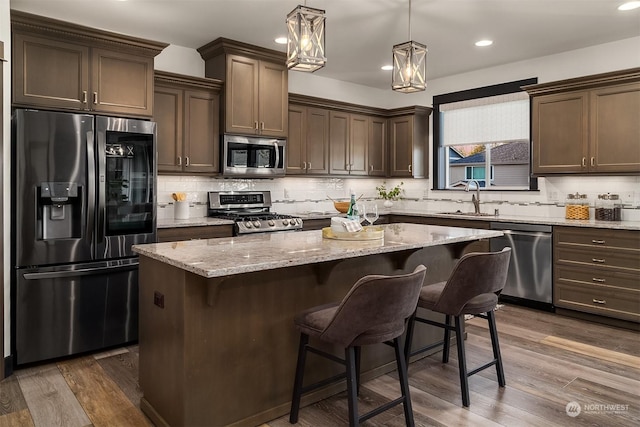 kitchen featuring dark hardwood / wood-style flooring, stainless steel appliances, a kitchen island, and hanging light fixtures