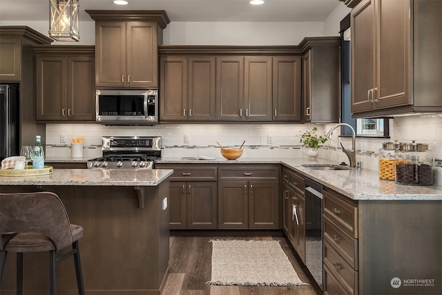 kitchen with a kitchen breakfast bar, light stone counters, sink, and appliances with stainless steel finishes