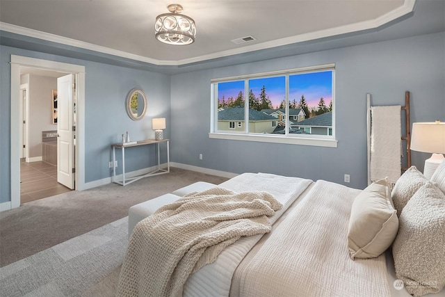 bedroom featuring carpet, a tray ceiling, ensuite bath, and ornamental molding