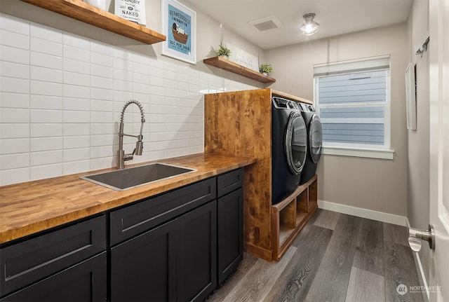 laundry room featuring cabinets, washer and clothes dryer, dark wood-type flooring, and sink