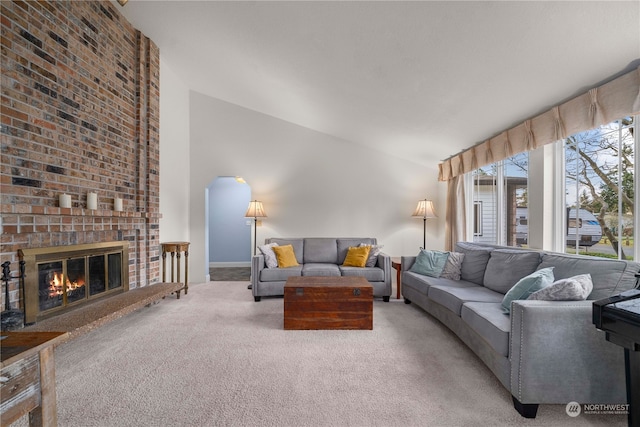 living room featuring carpet, vaulted ceiling, and a brick fireplace