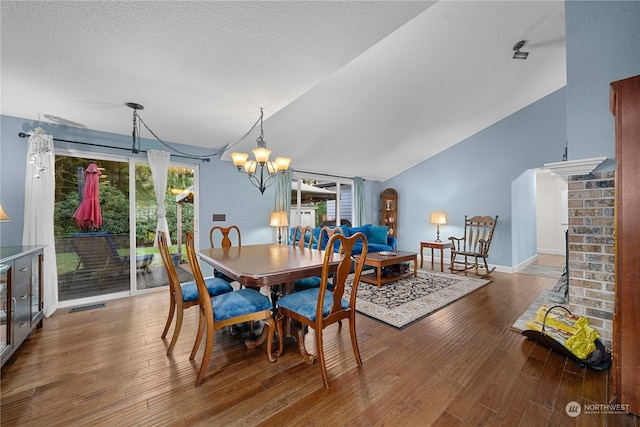 dining space featuring a chandelier, wood-type flooring, a textured ceiling, and vaulted ceiling