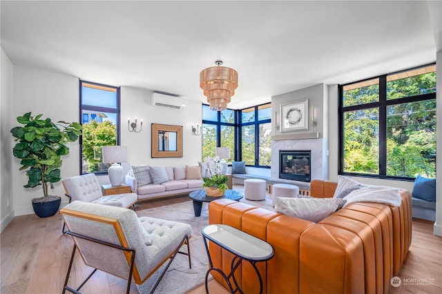 living room with a wall mounted AC, a chandelier, a high end fireplace, and light hardwood / wood-style floors