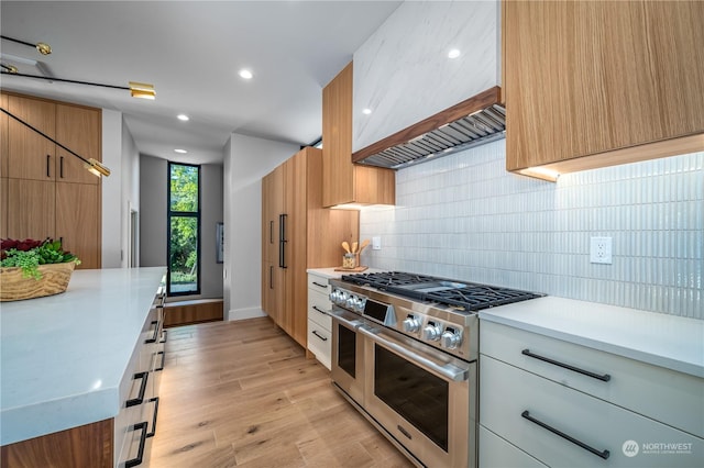 kitchen with backsplash, white cabinets, double oven range, and light hardwood / wood-style floors