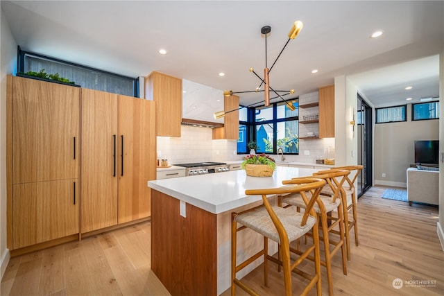 kitchen with a breakfast bar, a center island, light hardwood / wood-style floors, range, and a chandelier