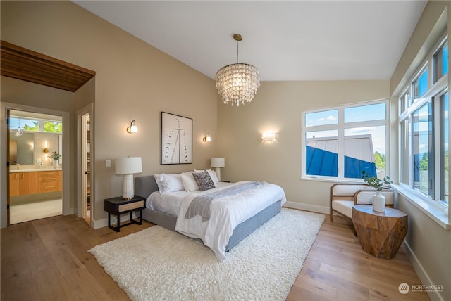 bedroom with an inviting chandelier, wood-type flooring, multiple windows, and ensuite bath