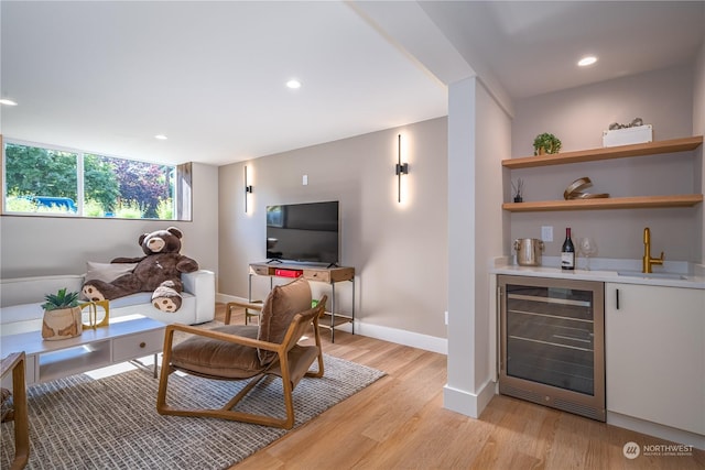 living room featuring wine cooler, light wood-type flooring, and indoor wet bar