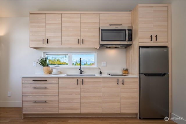 kitchen with hardwood / wood-style floors, light brown cabinets, sink, and stainless steel appliances