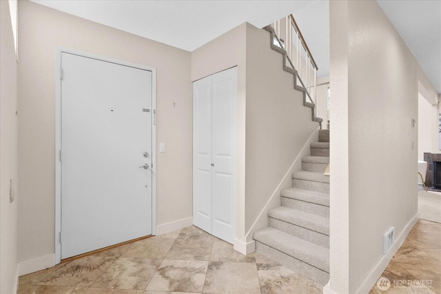 foyer with visible vents, stairway, and baseboards