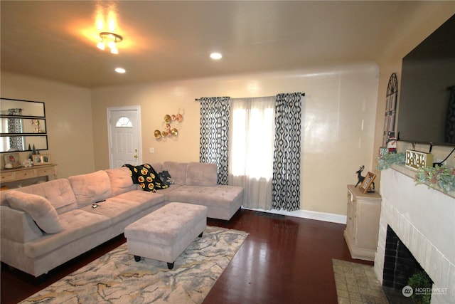 living room featuring dark hardwood / wood-style floors and a brick fireplace