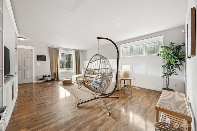 living area with a healthy amount of sunlight, wood-type flooring, and a textured ceiling