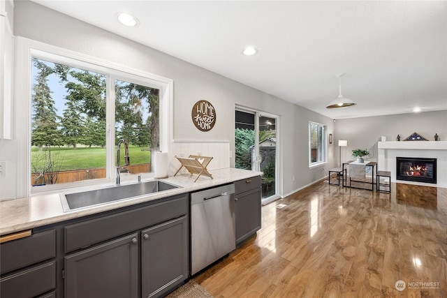 kitchen with a fireplace, light hardwood / wood-style floors, sink, dishwasher, and gray cabinets