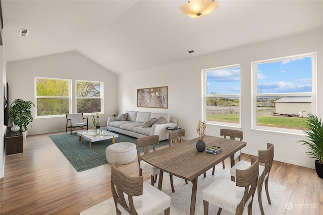 dining area featuring vaulted ceiling and light hardwood / wood-style flooring