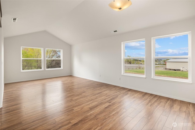 spare room featuring lofted ceiling and hardwood / wood-style floors