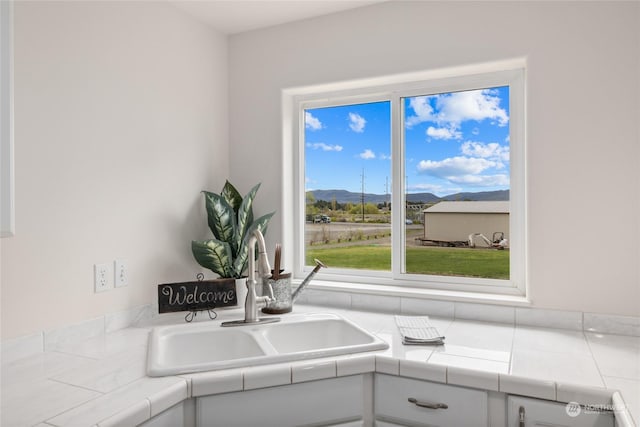 kitchen with white cabinetry, sink, tile countertops, and a mountain view