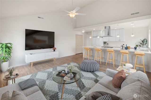 living room with hardwood / wood-style flooring, ceiling fan, lofted ceiling, and sink