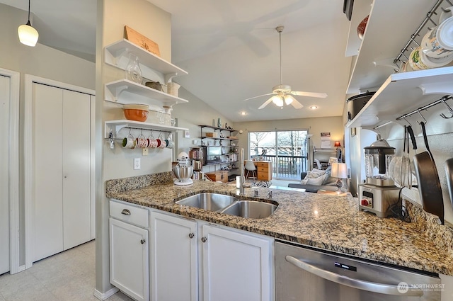 kitchen with ceiling fan, dark stone counters, vaulted ceiling, stainless steel dishwasher, and white cabinets