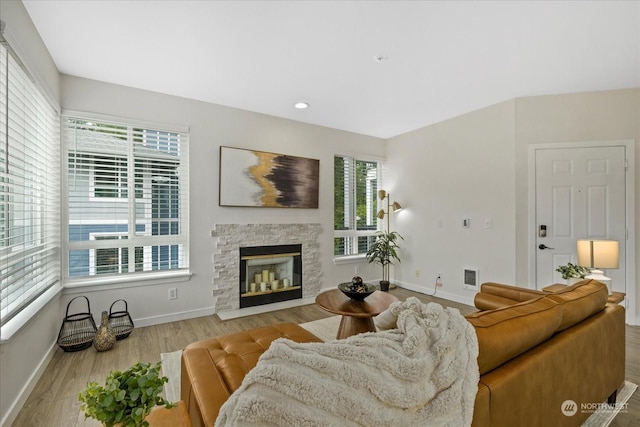 living room featuring light wood-type flooring, a fireplace, and plenty of natural light