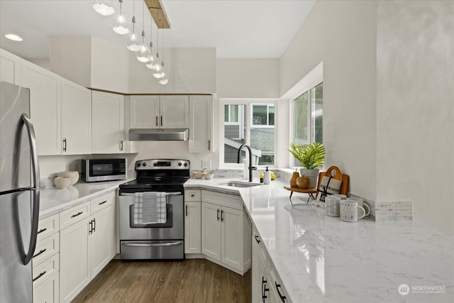 kitchen with white cabinetry, appliances with stainless steel finishes, decorative light fixtures, light stone countertops, and sink