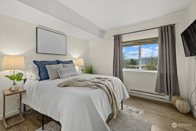 bedroom featuring baseboard heating and light hardwood / wood-style flooring