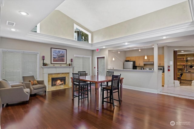 dining area with high vaulted ceiling, a high end fireplace, and dark wood-type flooring