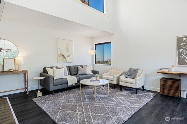 living room featuring a high ceiling, a textured ceiling, a wealth of natural light, and dark wood-type flooring