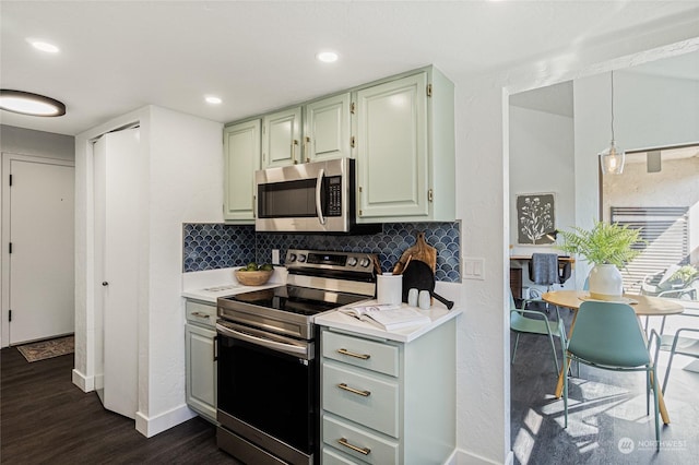 kitchen with decorative backsplash, appliances with stainless steel finishes, dark hardwood / wood-style flooring, and hanging light fixtures