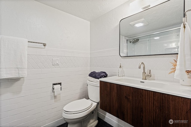 bathroom with vanity, a textured ceiling, tile walls, toilet, and a shower with shower door